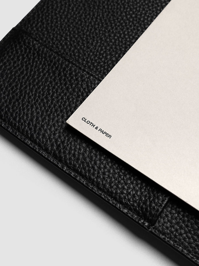 Close-up of the solid back panel corner of the A5 6-Ring Punch Diecut Pocket Folder, showing the printed Cloth and Paper logo against a black pebbled leather cover