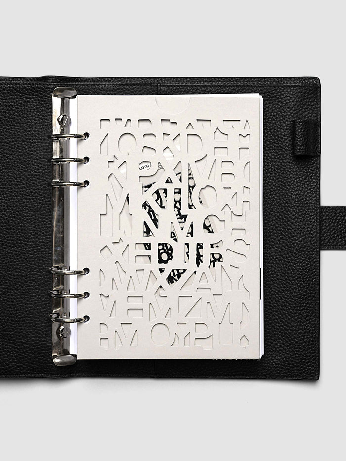 The A5 6-Ring Punch Diecut Pocket Folder holding printed pages inside a black leather ring bound planner, the contents showing through the cut letters