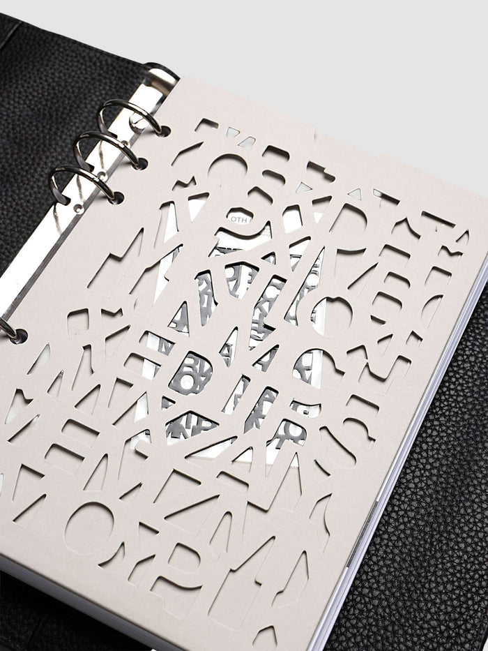 Close-up of the A5 6-Ring Punch Diecut Pocket Folder at an angle with pages stored inside, the printed contents visible through the cut letters