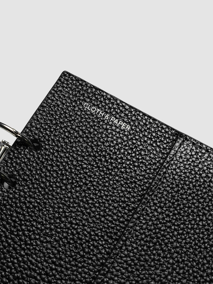 Close-up of the silver foiled Cloth and Paper logo on the pebbled black leather front cover of the A5 6-Ring Punch Genuine Leather Planner Cover Set