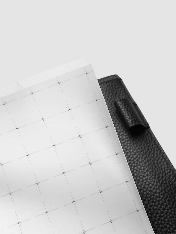 Grid Top Tab Dividers | Ultra-Thin, A5 6-Ring Punch, angled close-up of the top corner of a divider against black pebbled leather, showing the tab edge and the black crosshair grid
