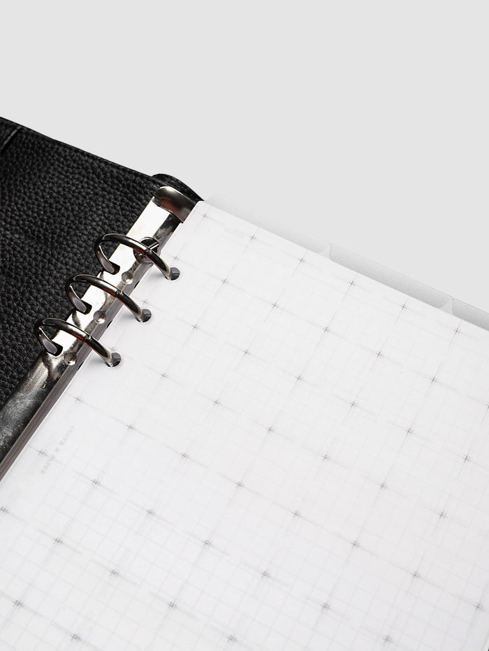 Grid Top Tab Dividers | Ultra-Thin, A5 6-Ring Punch, angled detail of the silver rings of a black leather ring bound planner with the grid printed divider opening away toward the tabs