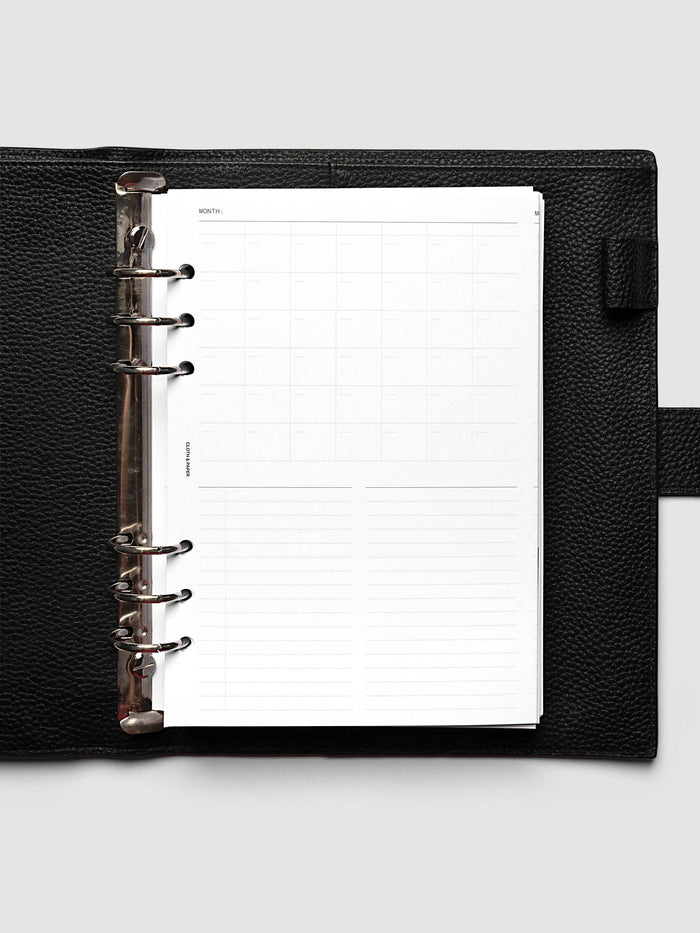 Monthly Fold Out Planner Insert Set of 2, A5 6-Ring Punch, the insert folded closed inside a black pebbled leather ring bound planner with silver rings, shot from directly above