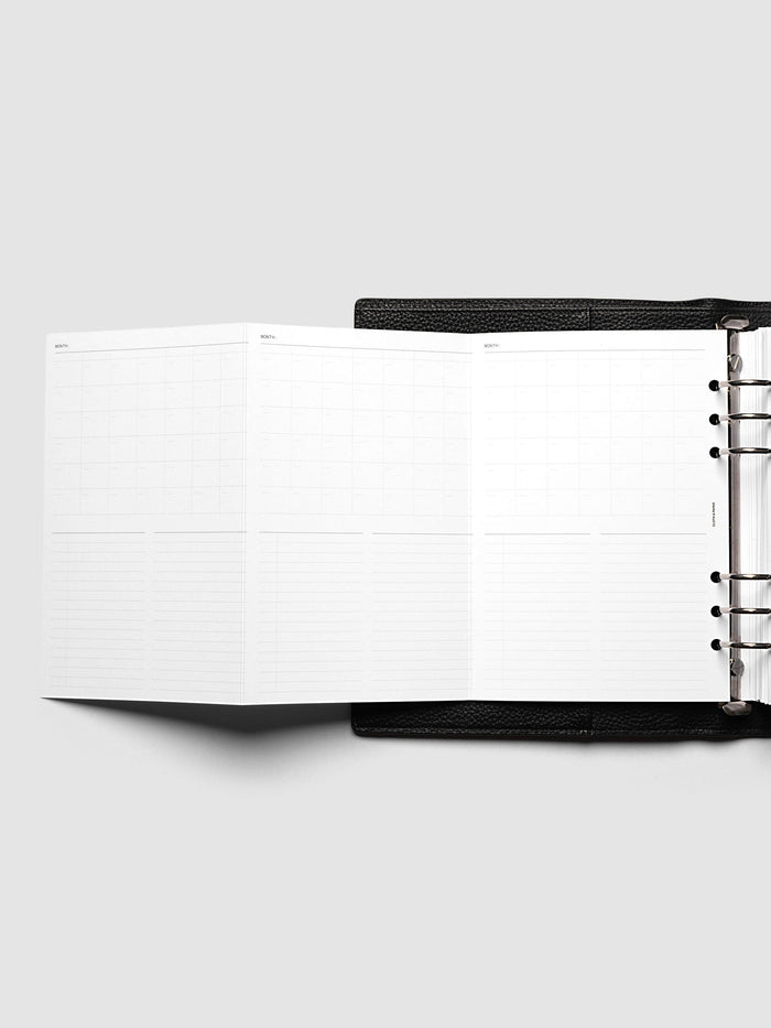 Monthly Fold Out Planner Insert Set of 2, A5 6-Ring Punch, the insert opened out to the left of a black leather ring bound planner, silver rings visible along the right edge of the frame