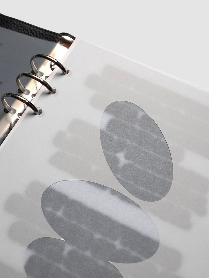 Nuanced Dashboard Trio, A5 6-Ring Punch, tight angled shot of the silver rings and two grey ovals, showing how the print sits over the page beneath