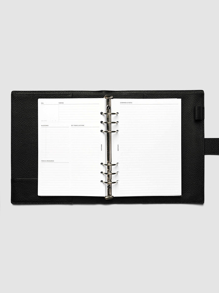 The A5 6-Ring Punch Personal Curriculum Planner Inserts open in a black leather ring bound planner to a skill spread, with skill, purpose, milestones, key tasks and resources on the left and lined learnings and notes on the right