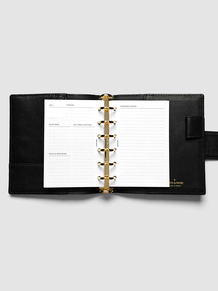 The Pocket Personal Curriculum Planner Inserts open in a black leather ring bound planner to a skill spread, with skill, purpose, milestones, key tasks and resources on the left and lined learnings and notes on the right