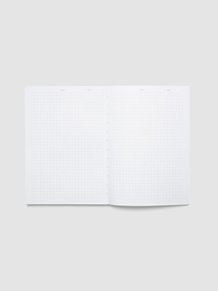 The Precision Notebook | A5 open flat to a graph paper spread, with a Focus and Date line across the top of each page