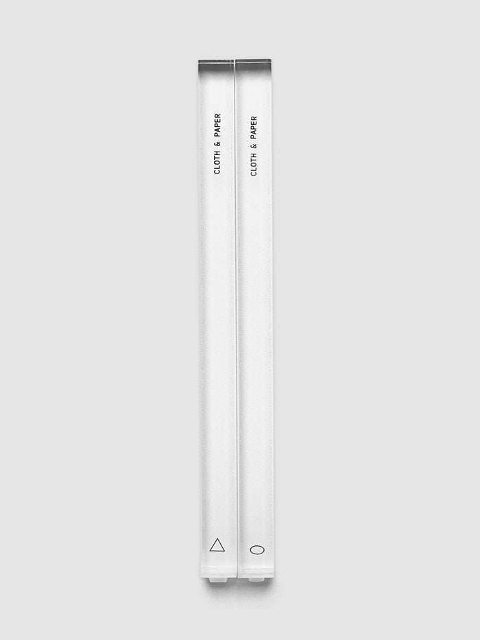 Stamp Sticks | Set of 2 laid side by side on a light gray background, clear shafts with the Cloth & Paper name printed in black and a small triangle and oval marked near the base of each
