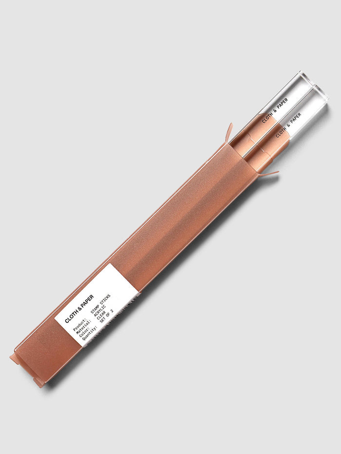 Stamp Sticks | Set of 2 in packaging, two clear sticks sliding out of a terracotta sleeve with a white label listing the product, material, color and quantity