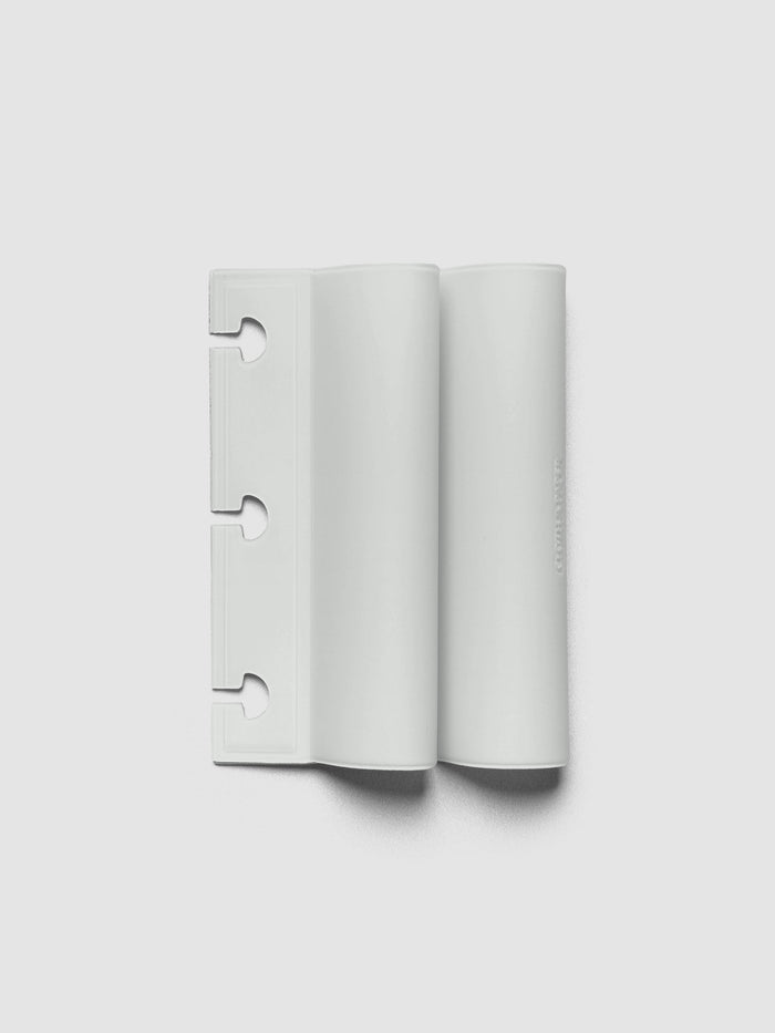 System Punch Pen Holder | Aspen, disc punch, pale gray holder shown flat with two rounded pen loops and mushroom shaped notches cut along the left edge on a light gray background